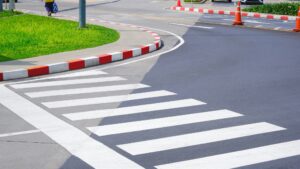 Pedestrian crosswalk with red and white stripes line on the edge of footpath in car parking area